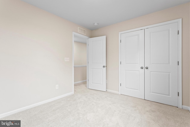 unfurnished bedroom featuring carpet floors, baseboards, a closet, and visible vents