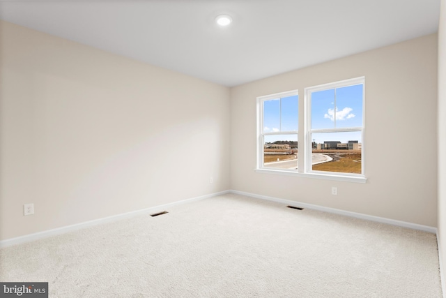 carpeted spare room featuring baseboards and visible vents