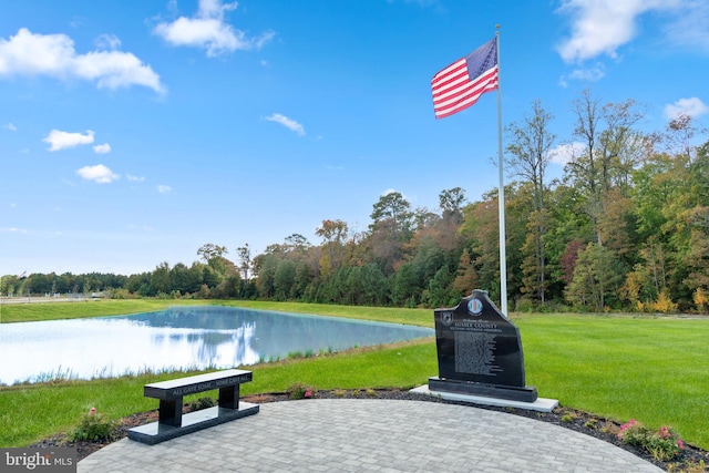 view of home's community with a lawn, a water view, and a view of trees
