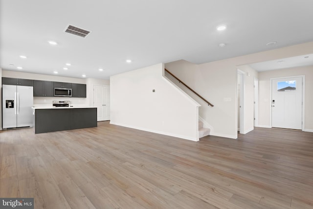 unfurnished living room featuring visible vents, stairs, baseboards, light wood finished floors, and recessed lighting