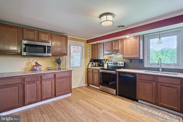 kitchen featuring a sink, light countertops, stainless steel appliances, under cabinet range hood, and ornamental molding