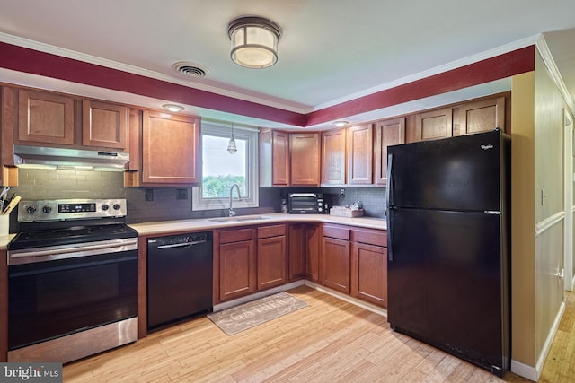 kitchen with a sink, under cabinet range hood, black appliances, and light countertops