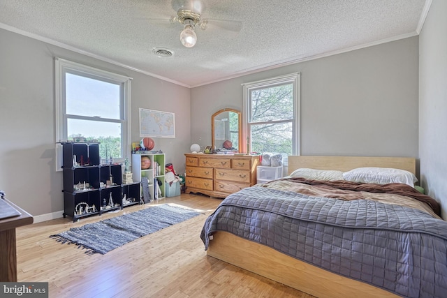 bedroom with crown molding, visible vents, wood finished floors, ceiling fan, and a textured ceiling
