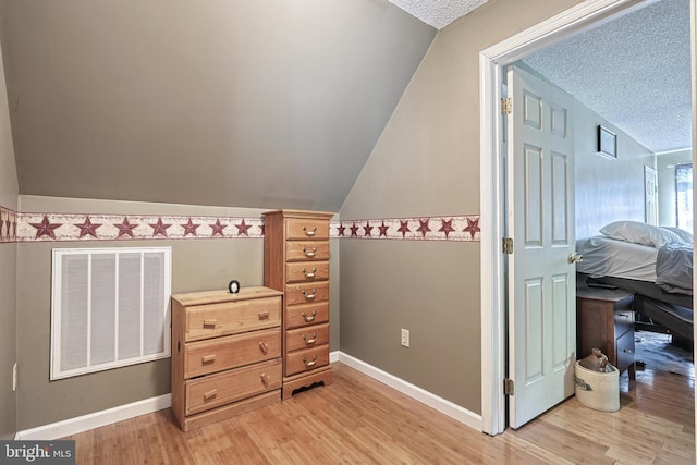 bonus room featuring light wood-style floors, a textured ceiling, lofted ceiling, and visible vents