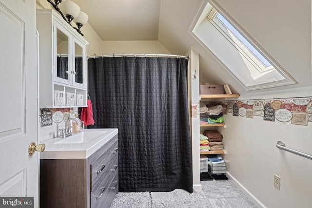 bathroom with a skylight, vanity, and baseboards