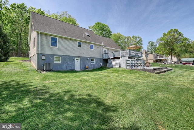 rear view of property featuring central AC unit, a yard, and a deck