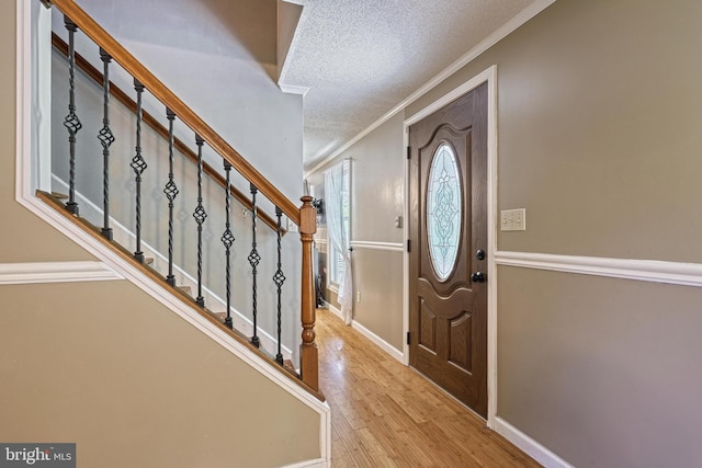 entrance foyer with crown molding, a textured ceiling, stairs, baseboards, and wood finished floors