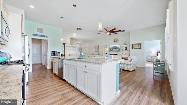 kitchen featuring light wood finished floors, a sink, open floor plan, visible vents, and appliances with stainless steel finishes