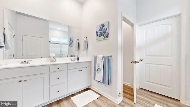 bathroom featuring a stall shower, double vanity, a sink, and wood finished floors
