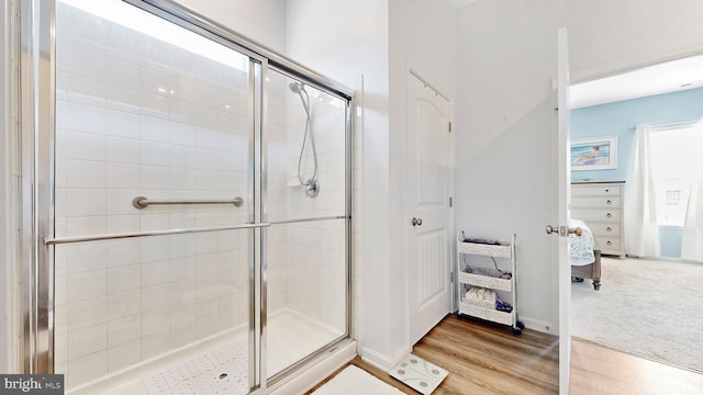 full bath featuring ensuite bath, wood finished floors, and a shower stall