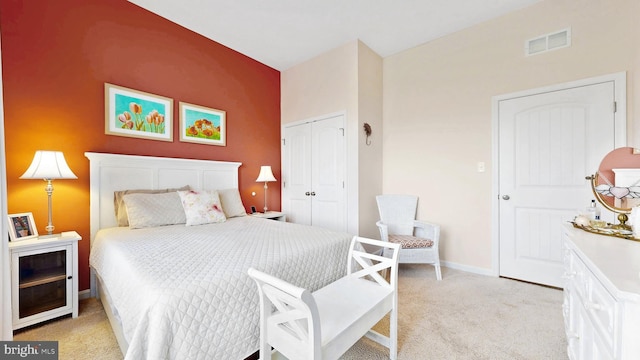 bedroom featuring a closet, visible vents, baseboards, and light carpet