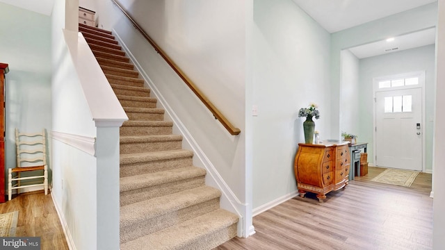 foyer entrance featuring light wood-style floors, visible vents, baseboards, and stairs
