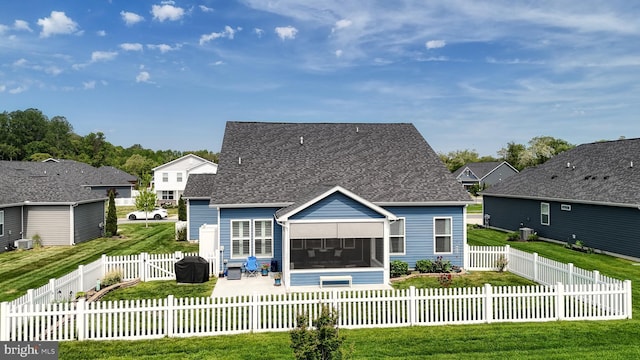 back of property with a yard, a patio area, a sunroom, a shingled roof, and a fenced backyard