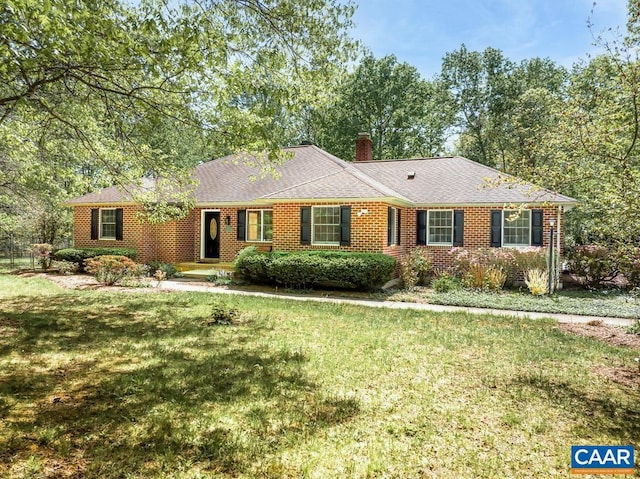 ranch-style home with brick siding, a chimney, and a front yard