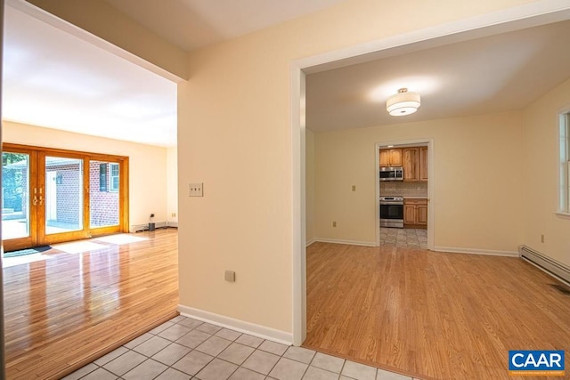 spare room with baseboards, french doors, baseboard heating, and light wood-style floors