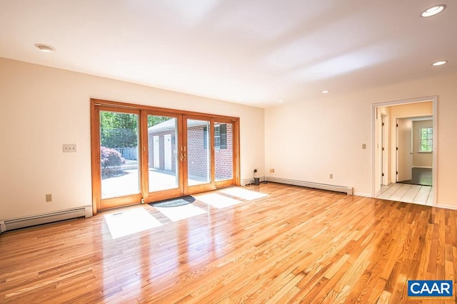 empty room featuring a baseboard radiator, recessed lighting, plenty of natural light, and wood finished floors