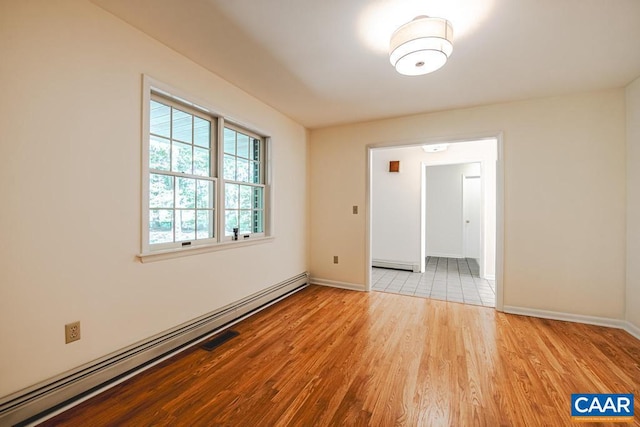 spare room with baseboards, wood finished floors, a baseboard radiator, and a baseboard heating unit