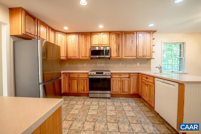 kitchen with recessed lighting, decorative backsplash, light countertops, stone finish flooring, and appliances with stainless steel finishes