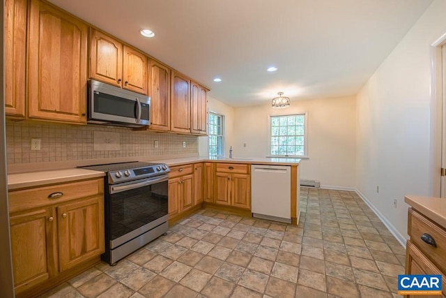 kitchen with baseboards, a peninsula, light countertops, tasteful backsplash, and appliances with stainless steel finishes