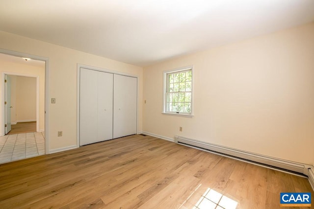 unfurnished bedroom with a closet, light wood-style floors, baseboards, and a baseboard radiator