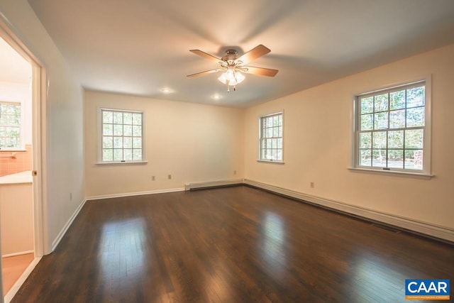 spare room with a ceiling fan, plenty of natural light, and dark wood-type flooring