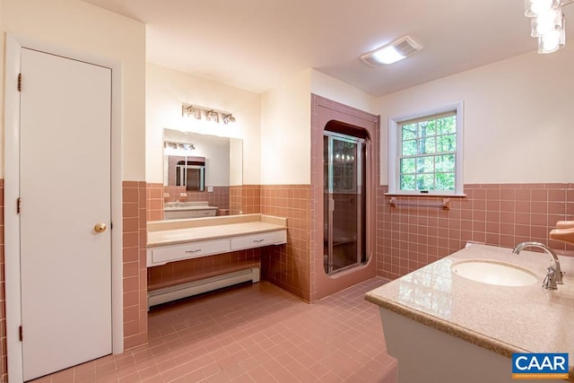bathroom featuring tile walls, tile patterned flooring, a shower stall, baseboard heating, and wainscoting
