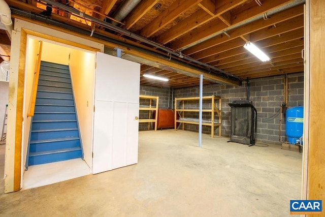 unfinished below grade area featuring a wood stove and stairway