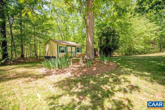 view of yard featuring a wooded view, an outbuilding, and a shed
