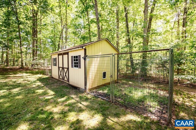 view of shed featuring fence and a view of trees