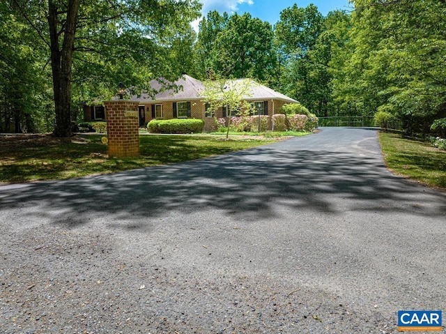 ranch-style home with fence and aphalt driveway