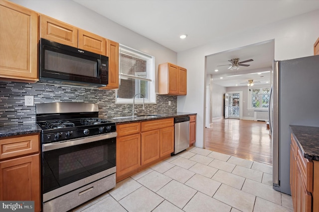 kitchen featuring backsplash, ceiling fan, a sink, appliances with stainless steel finishes, and light tile patterned floors
