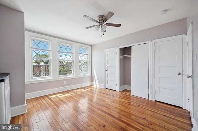 unfurnished bedroom featuring baseboards, a closet, hardwood / wood-style flooring, and ceiling fan