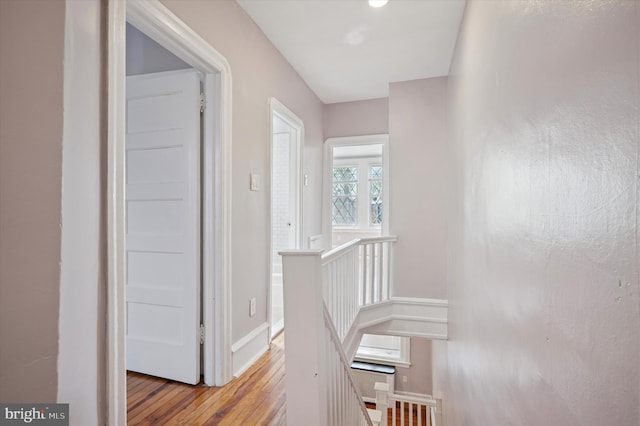 hall featuring baseboards, an upstairs landing, and light wood-style flooring