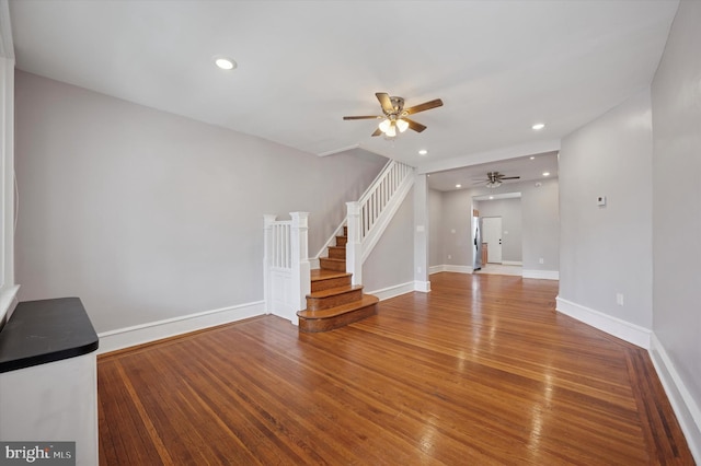 unfurnished living room with a ceiling fan, stairs, wood finished floors, baseboards, and recessed lighting