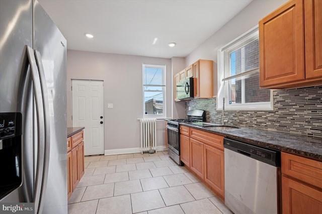 kitchen featuring a sink, radiator, stainless steel appliances, decorative backsplash, and light tile patterned floors