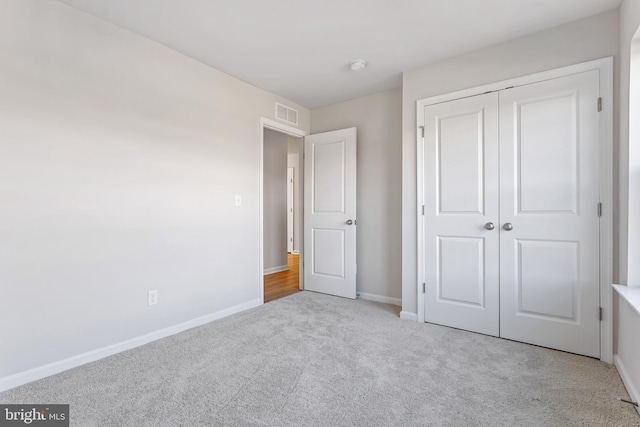 unfurnished bedroom featuring baseboards, visible vents, carpet, and a closet