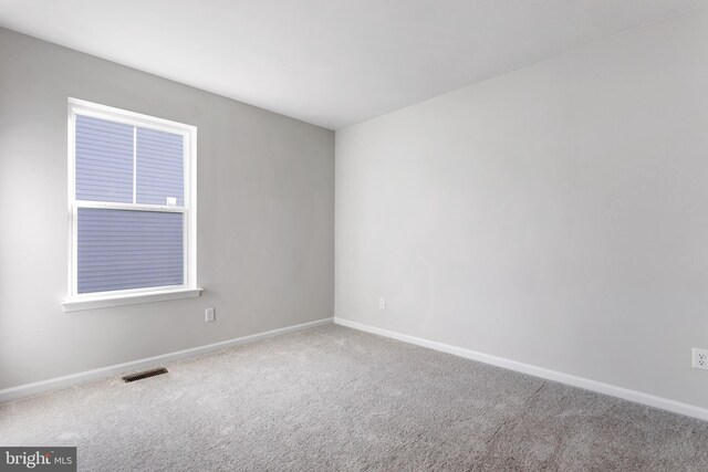 carpeted spare room featuring baseboards and visible vents