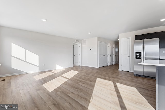 unfurnished living room featuring recessed lighting, baseboards, and light wood finished floors