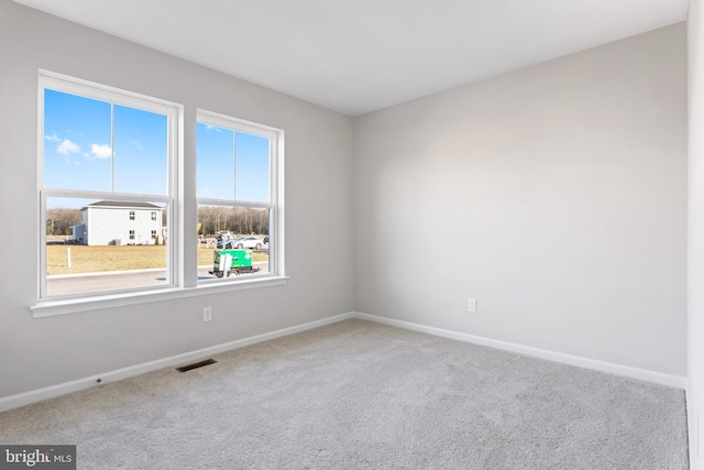 carpeted spare room with visible vents and baseboards