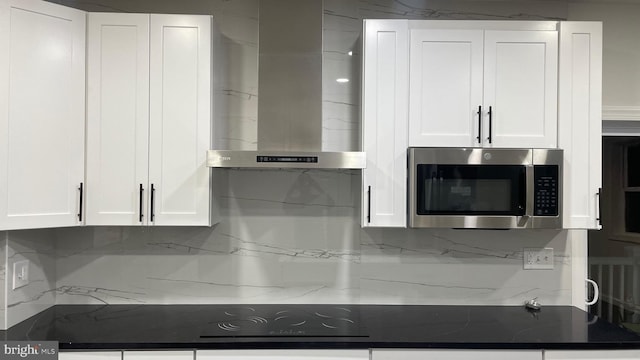 123 Cumberland St, Cumberland, MD 21502 - kitchen with wall chimney range hood, decorative backsplash, stainless steel microwave, dark stone counters, and white cabinetry