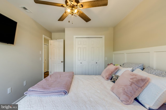 bedroom featuring a wainscoted wall, ceiling fan, a closet, and visible vents