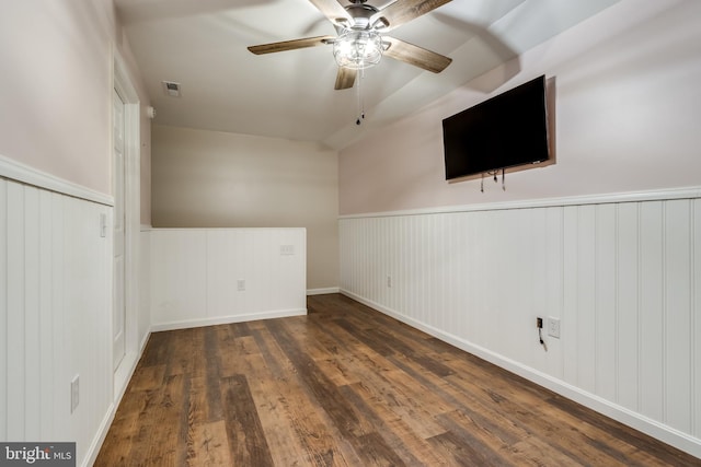 unfurnished room with a wainscoted wall, ceiling fan, wood finished floors, and visible vents