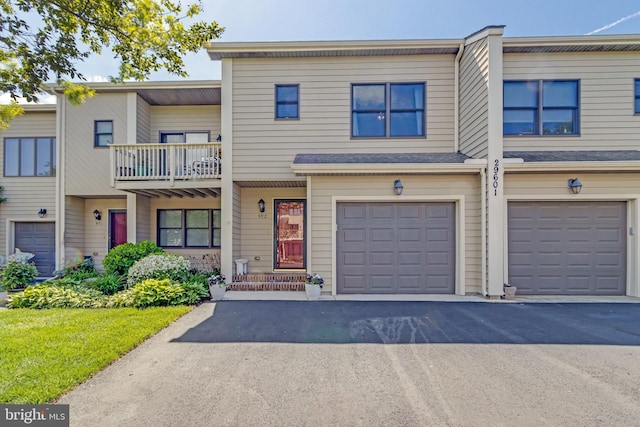 multi unit property featuring a garage, driveway, and a balcony