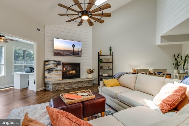 living area featuring wood finished floors, a fireplace, baseboards, ceiling fan, and high vaulted ceiling