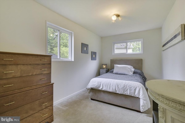bedroom featuring baseboards, light carpet, and a wall mounted air conditioner