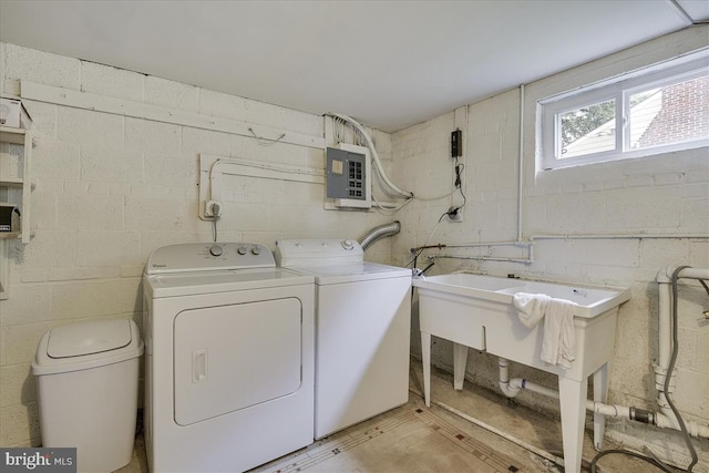 washroom featuring concrete block wall, laundry area, electric panel, and washer and clothes dryer