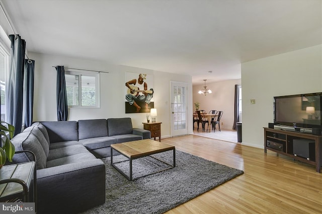 living room featuring baseboards, a chandelier, and light wood-type flooring