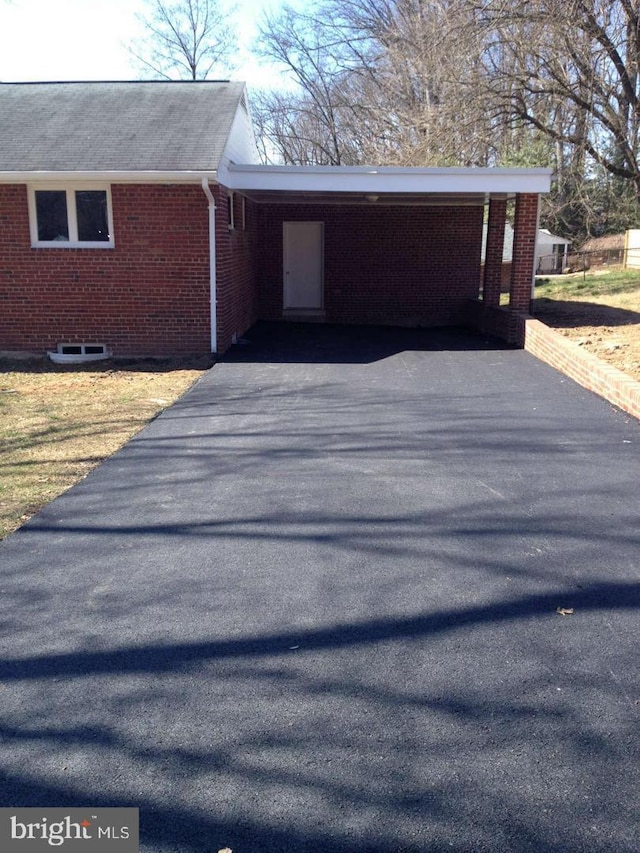 view of side of home with brick siding, driveway, and an attached carport
