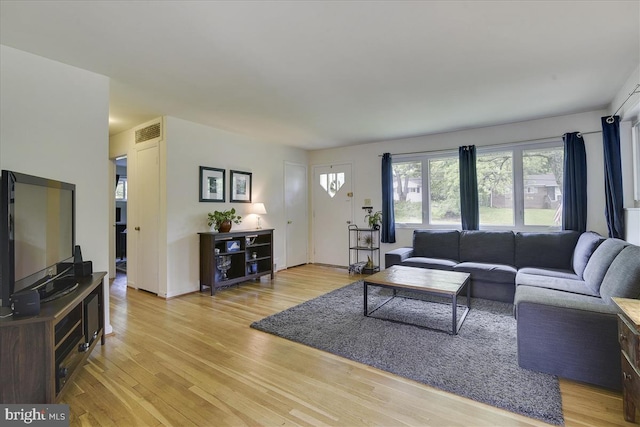 living area with visible vents, light wood-style floors, and baseboards