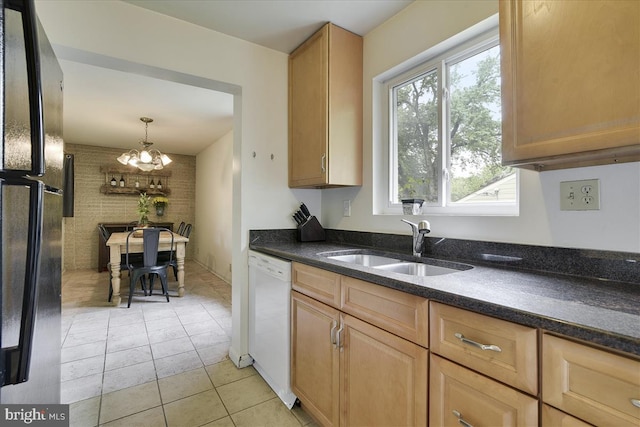kitchen featuring freestanding refrigerator, white dishwasher, a sink, light tile patterned floors, and a notable chandelier